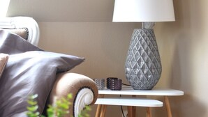 Une pièce confortable avec un canapé, une lampe, une petite table et une plante en pot.