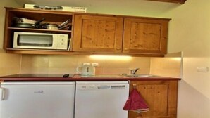 A compact kitchen with wooden cabinets, a microwave, a dishwasher, and a kettle. - 3-room apartment, 2 bathrooms, direct access to slopes (Plagne Soleil)