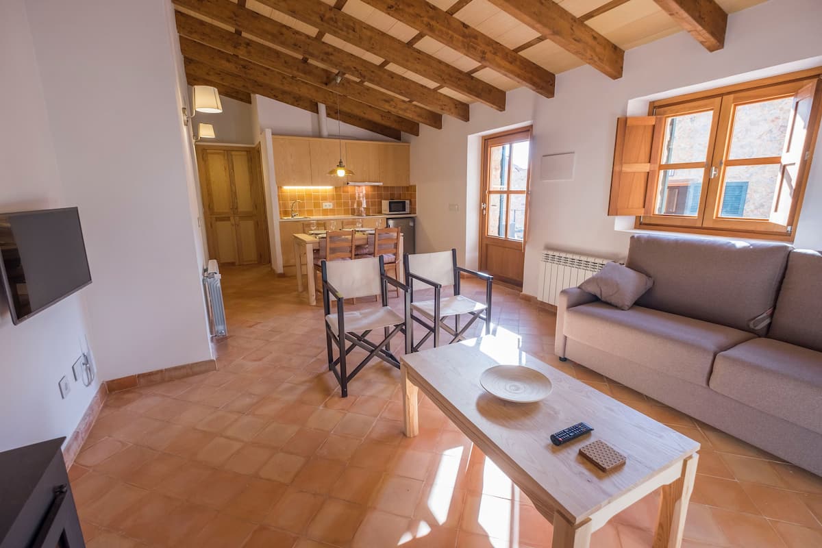 Amplia sala de estar con techo de madera, un sofá, una mesa de centro y un comedor con sillas y una mesa.