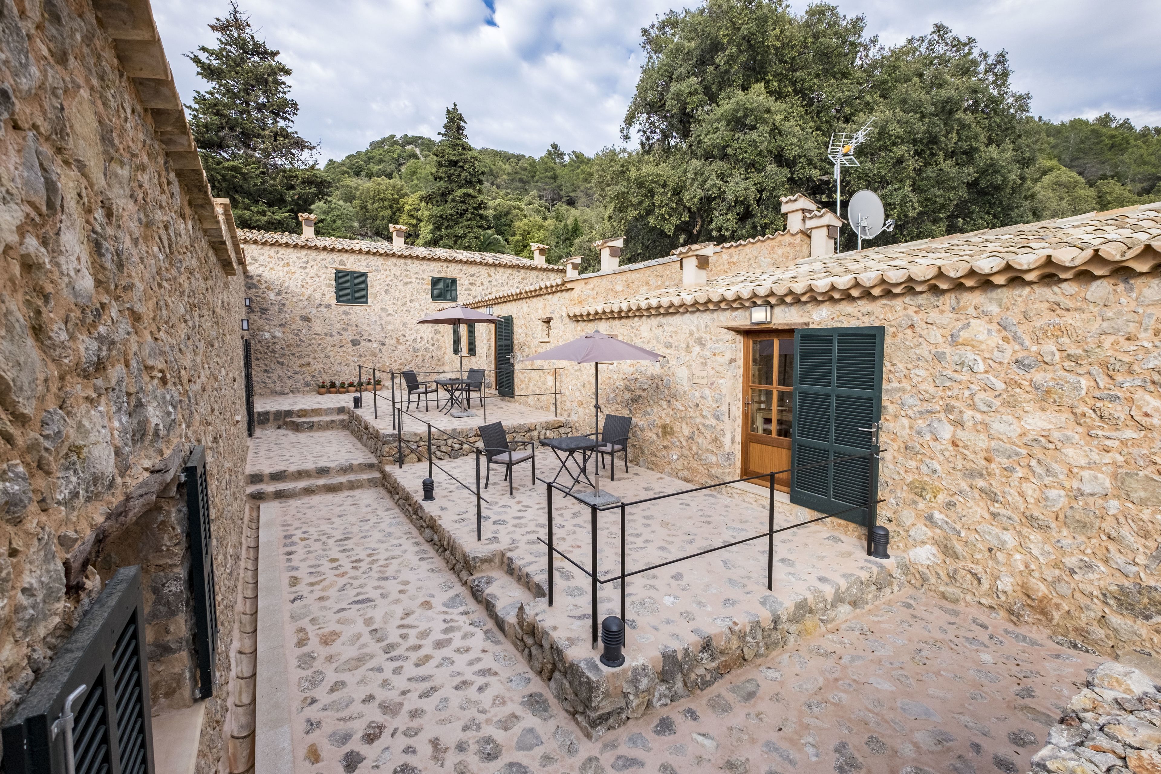 Un patio de piedra con mobiliario exterior y un edificio rústico.