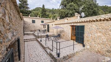 Un patio de piedra con mobiliario exterior y un edificio rústico.