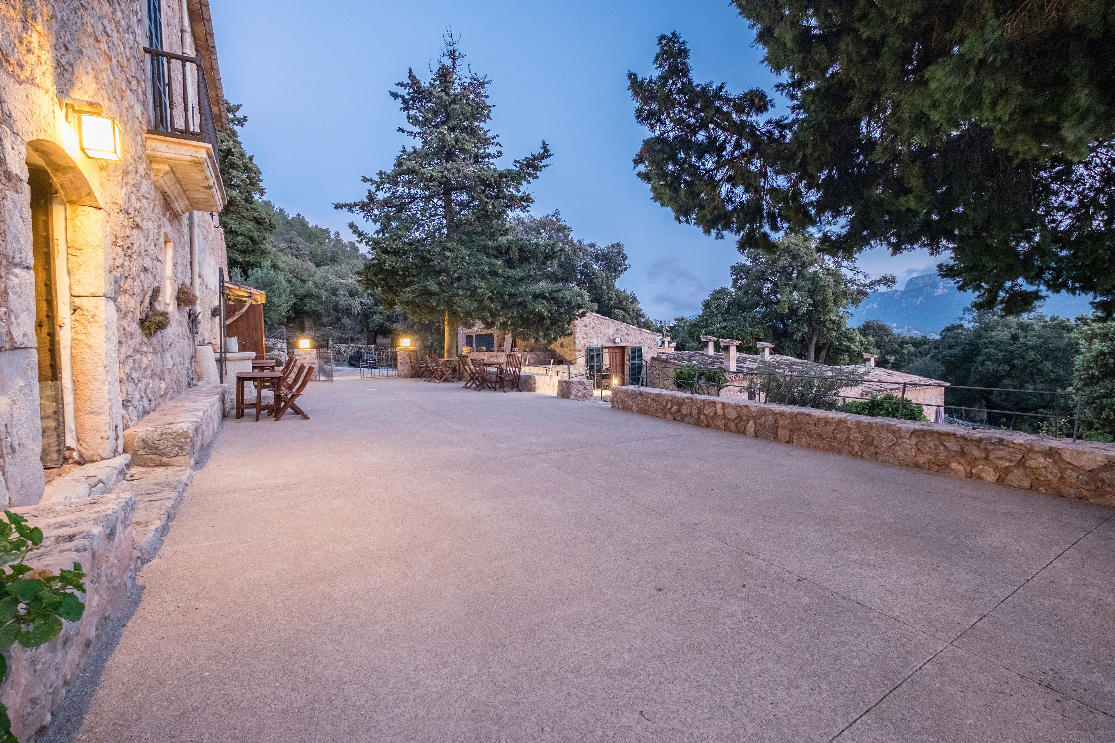 A stone building with outdoor seating and a view of trees and mountains.