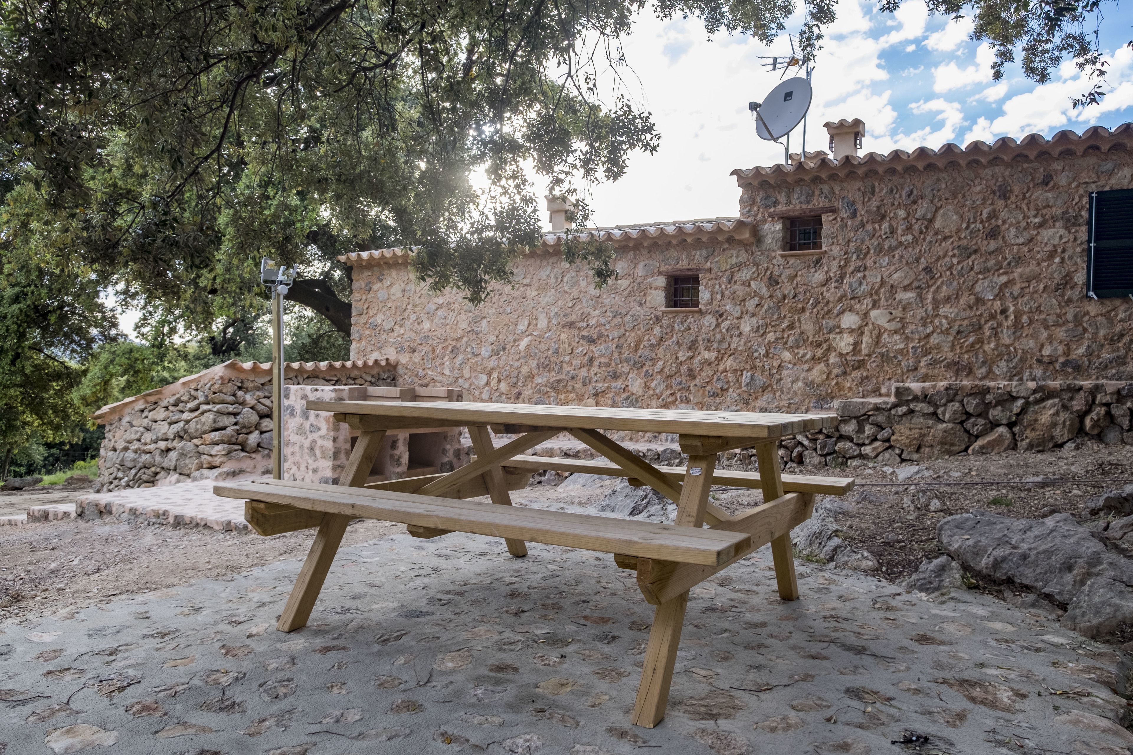 A rustic stone building with a wooden picnic table in front.
