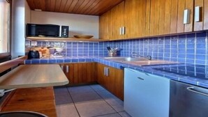 Una cocina moderna con armarios de madera, salpicadero de azulejos azules y electrodomésticos de acero inoxidable.