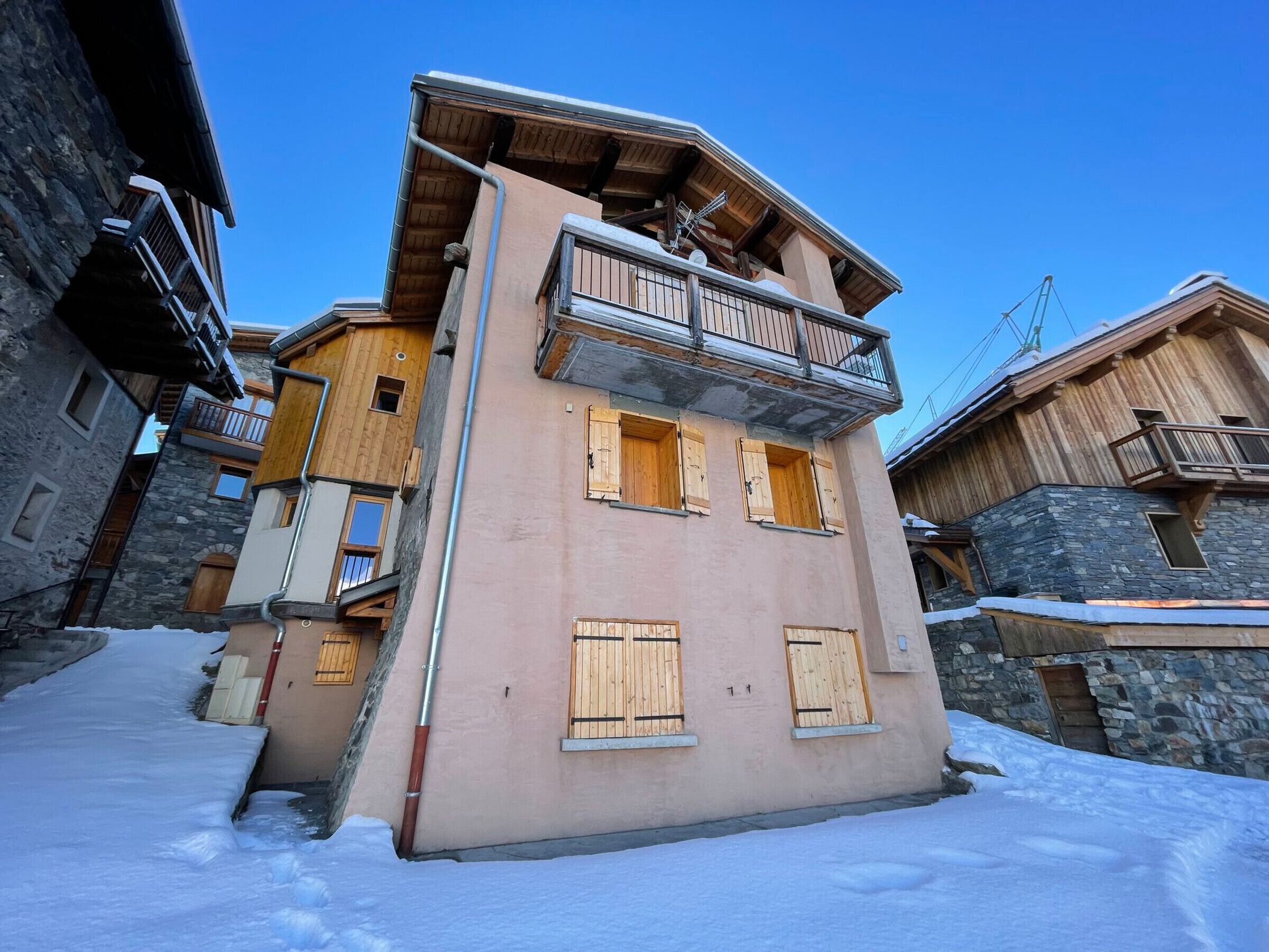 A multi-story building with wooden balconies and stone facades, surrounded by snow.