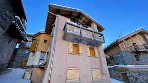 Un edificio de varios pisos con balcones de madera y fachadas de piedra, rodeado de nieve.