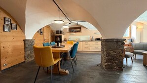 Un comedor amplio con un techo abovedado alto, una columna de piedra y una cocina moderna al fondo.