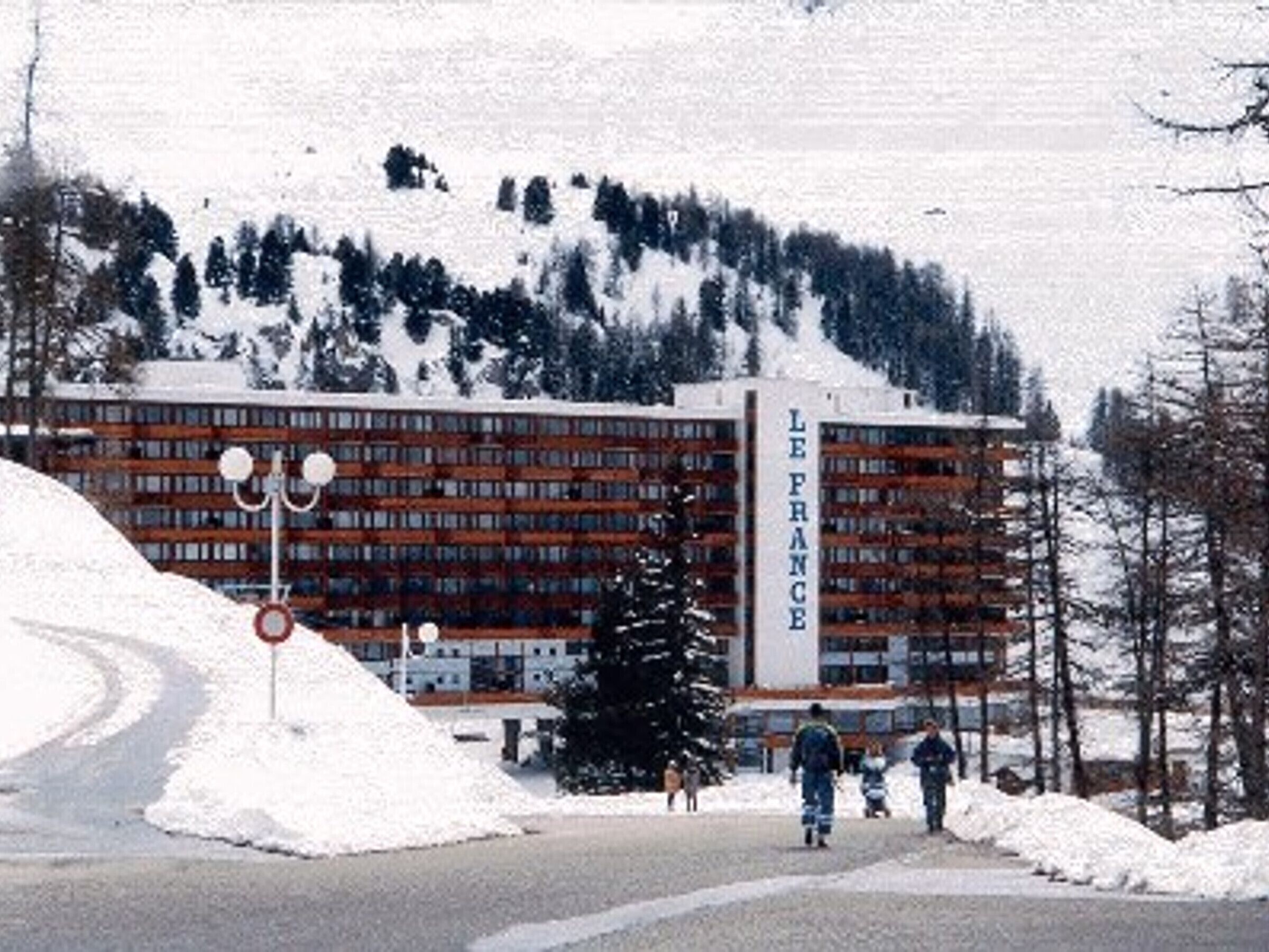 Un edificio con un cartello che riporta 'LE FRANCE' e un paesaggio innevato con una strada che vi conduce.