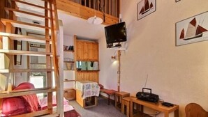 A cozy room with a loft bed, wooden shelves, a television, and a radio. - Duplex for 5/6 at the slopes with balcony (La Plagne)