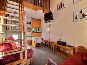 Ein gemütliches Zimmer mit Schlafkoje, Holzböden, einem Fernseher und einem Radio.