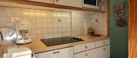 A compact kitchen with white cabinets, a microwave, a coffee maker, and a small refrigerator.
