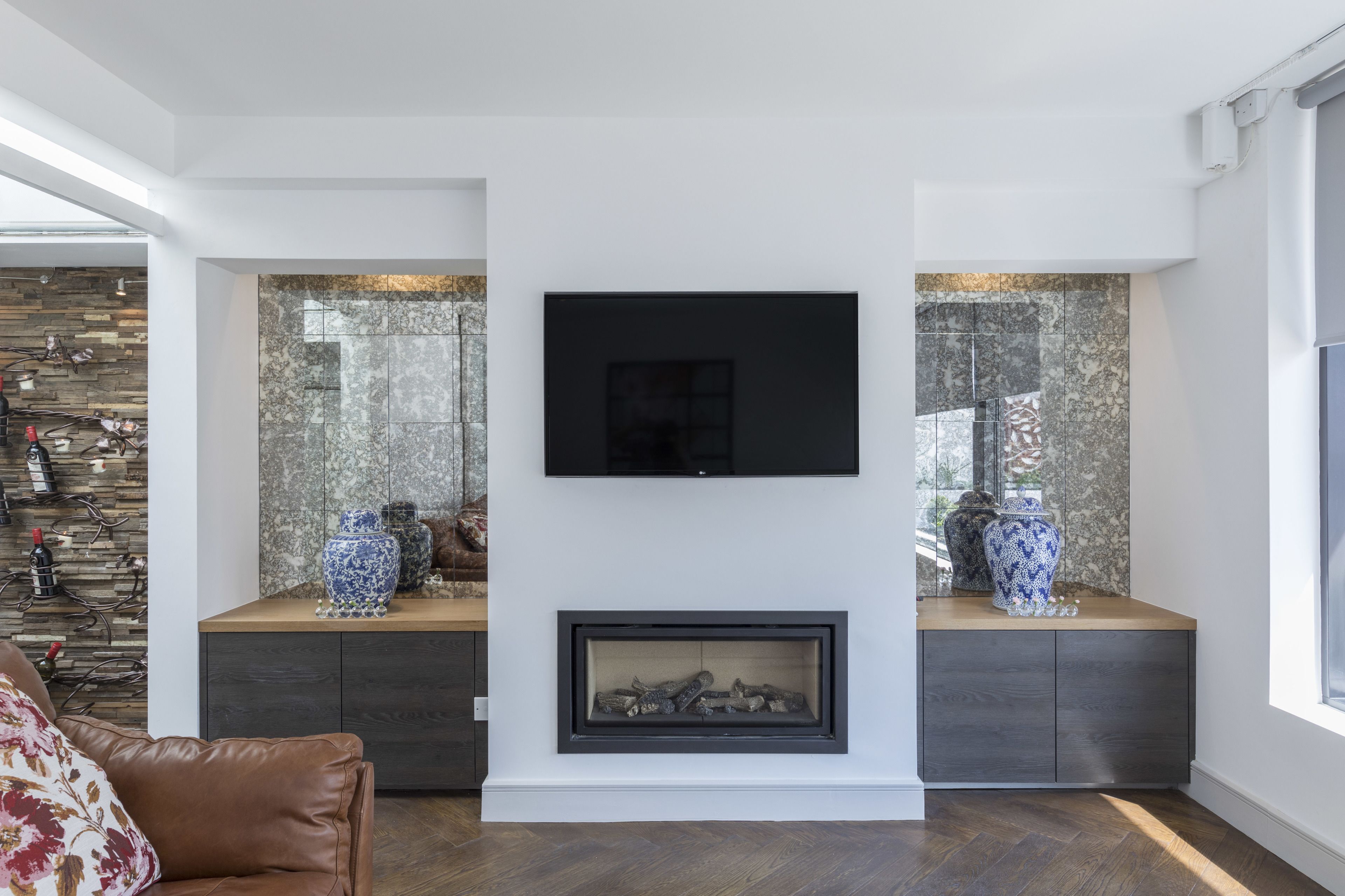 Un salon moderne avec une cheminée, un téléviseur fixé au mur et des vases décoratifs.