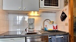 Ett kompakt kök med mikrovågsugn, kaffebryggare och diskho.