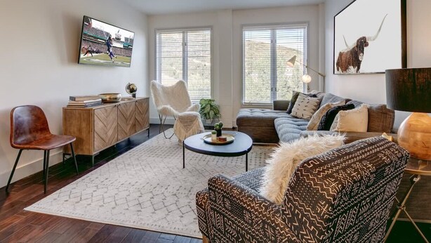 A modern living room with a sofa, armchair, coffee table, and a TV mounted on the wall.