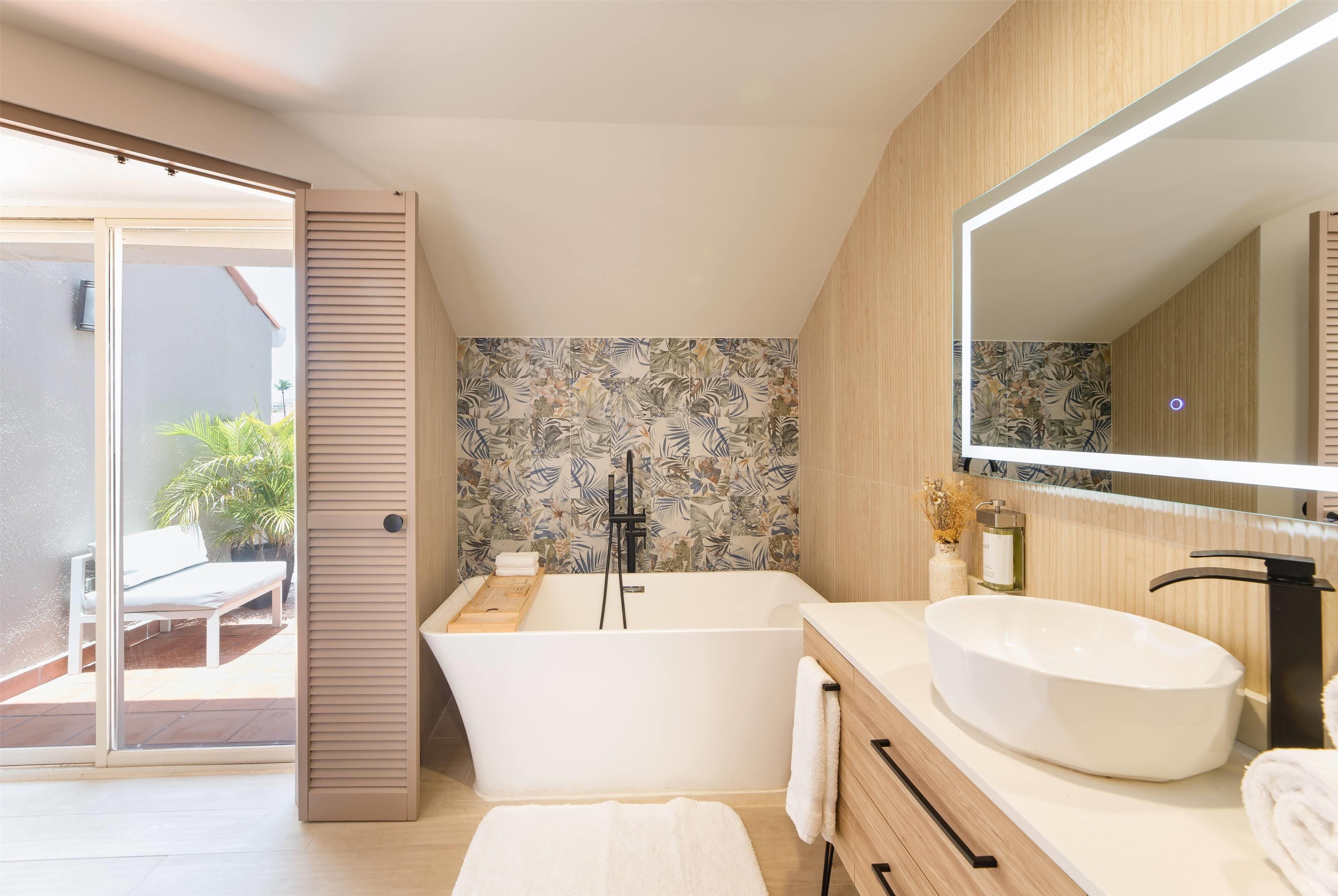 A modern bathroom with a freestanding bathtub, a large mirror, and a white sink.