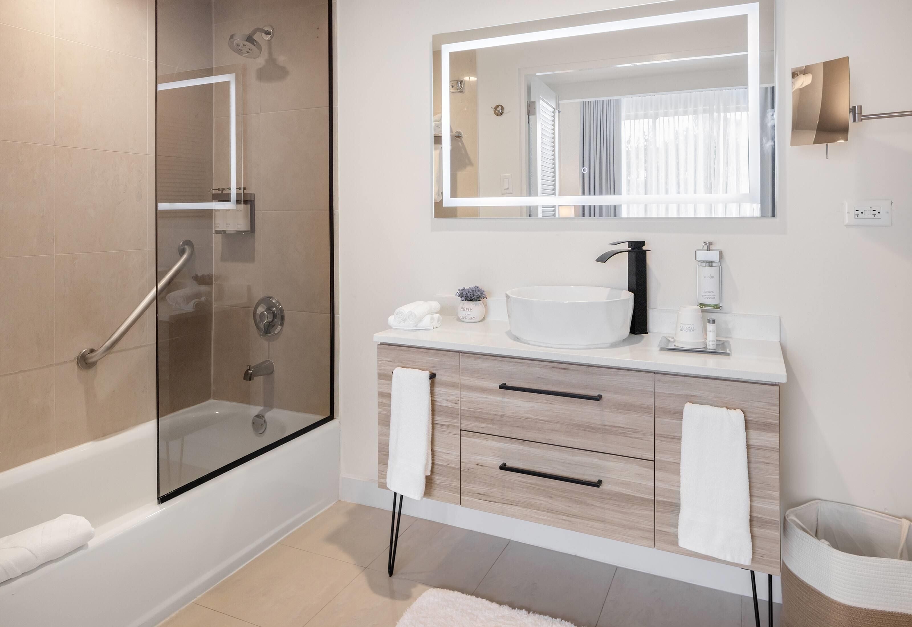 Une salle de bain moderne avec une douche à parois de verre, un lavabo blanc et un grand miroir.