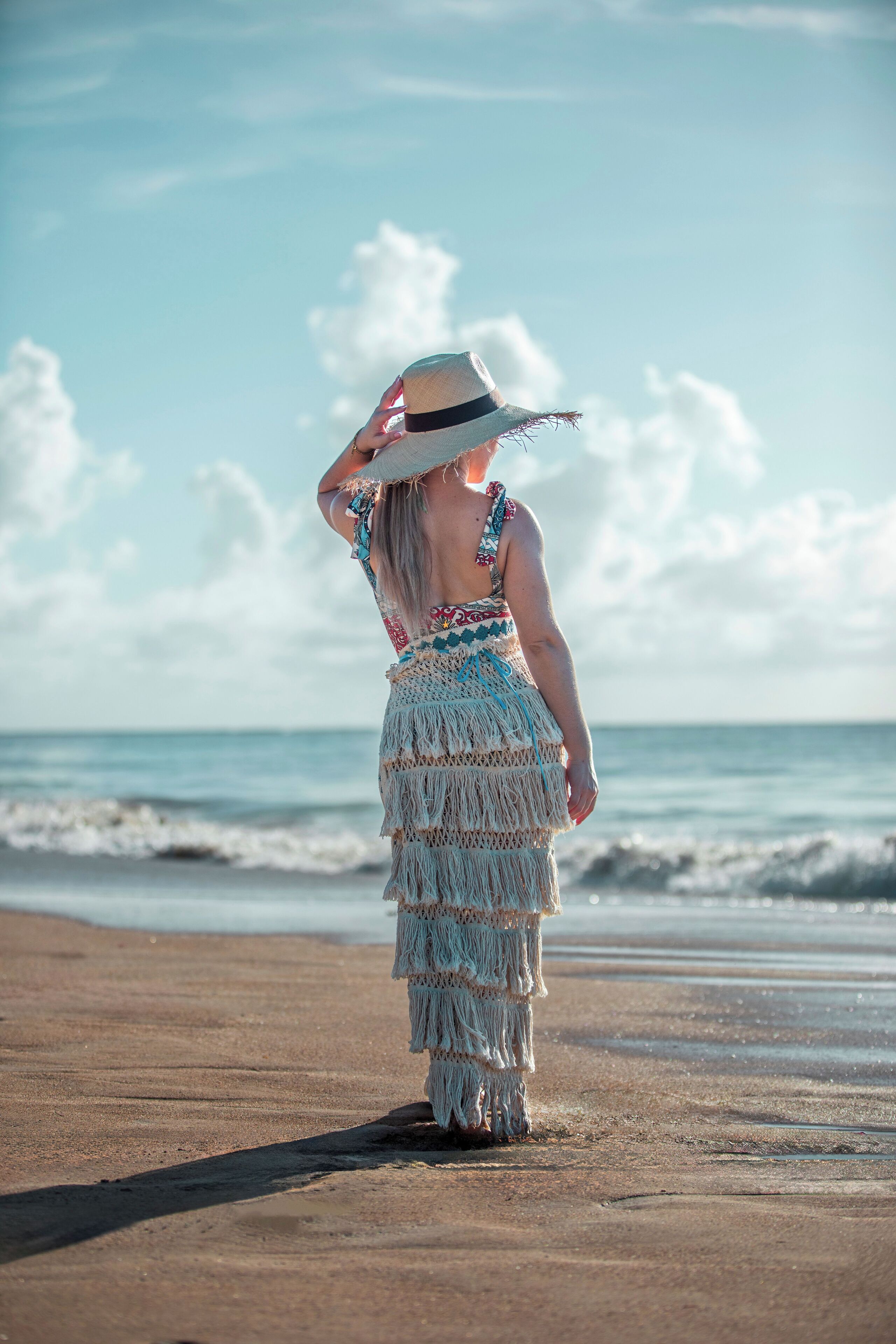 A person standing on a beach with waves in the background.