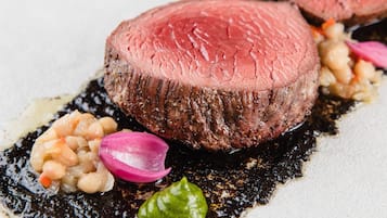 Ein Steak mit dunkler Sauce, garniert mit eingelegten Gemüsen und grüner Sauce.