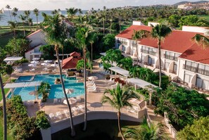 A resort with a swimming pool, lounge chairs, and palm trees. - Wyndham Palmas Beach and Golf Boutique Resort (Humacao)