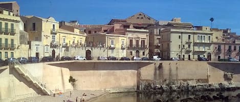 A coastal town with historic buildings, a beach, and rocky shoreline.