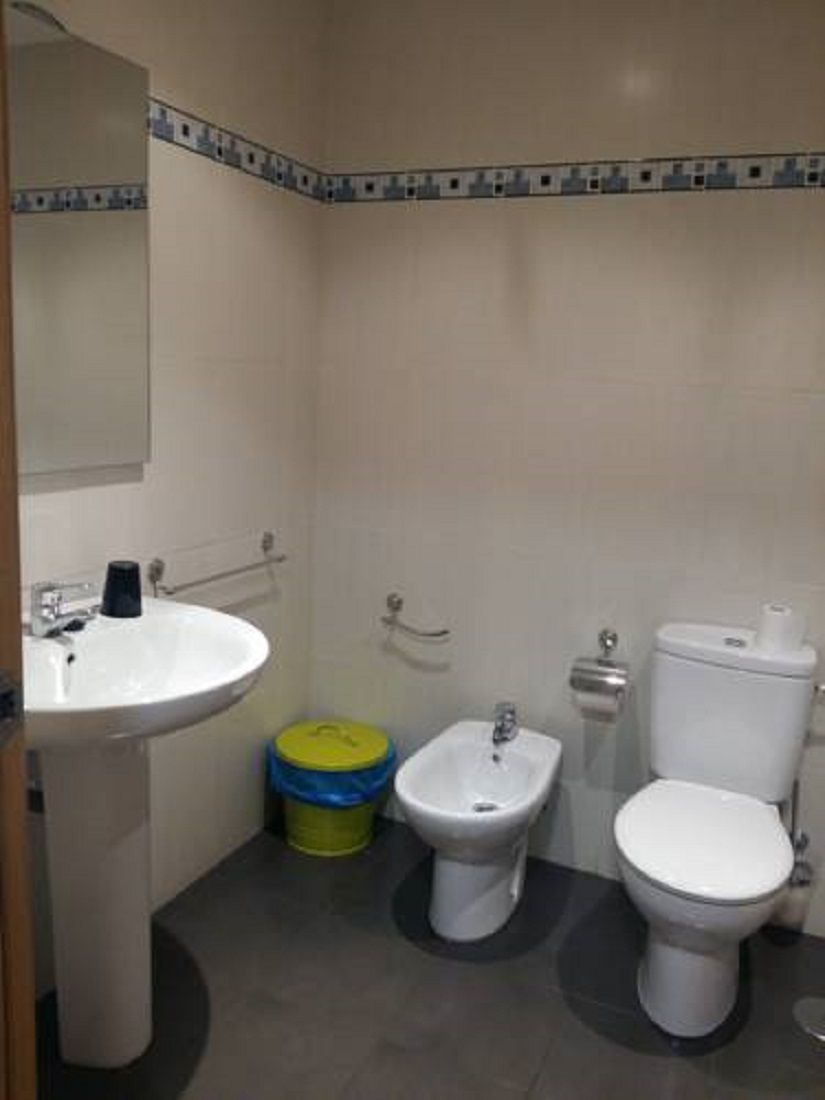 A small bathroom with a sink, bidet, toilet, and a mirror.