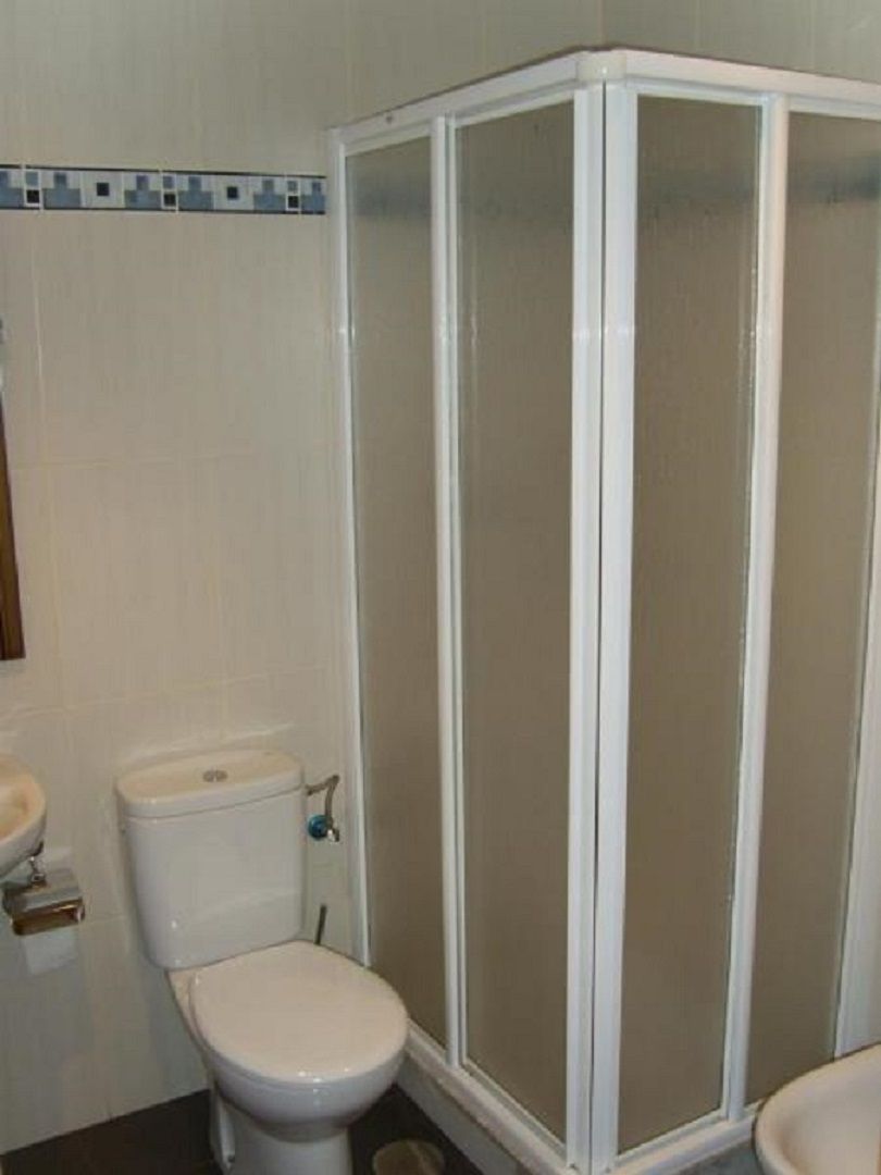 A bathroom with a toilet, a shower enclosure, and a sink.