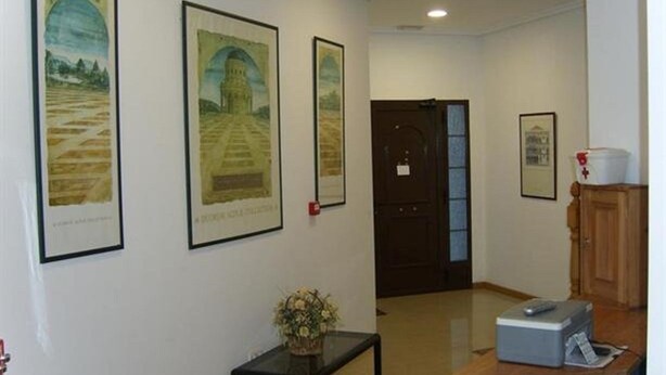 A hallway with framed artwork on the walls, a small table with a vase, and a wooden counter with a printer. - Hostal Las Eras (Cubillos del Sil)
