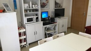 A compact kitchen with white cabinets, a microwave, a toaster, and a computer setup. - Hostal Las Eras (Cubillos del Sil)