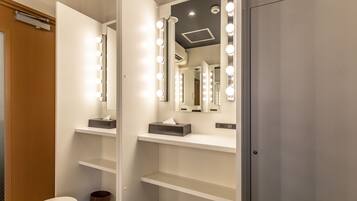 Un baño con tocador, espejo con iluminación y armario.