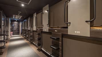 A row of hotel rooms with individual door handles, a carpeted floor, and a staircase in the background.