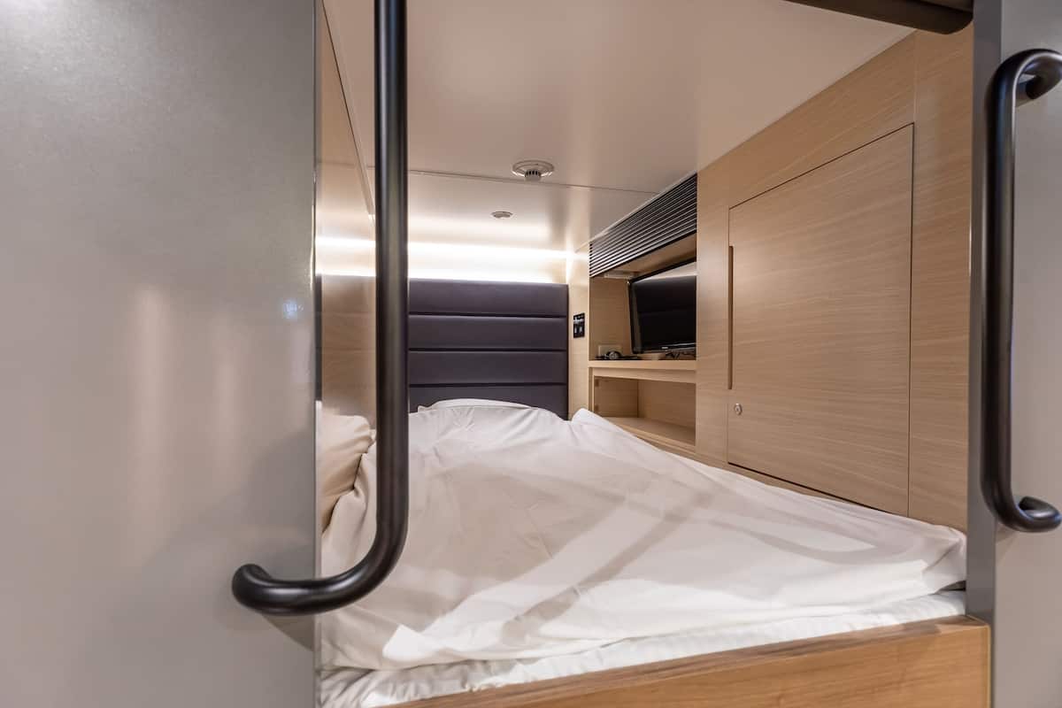 Een compacte, moderne slaapkamer met een bed, een klein bureau en een garderobe.