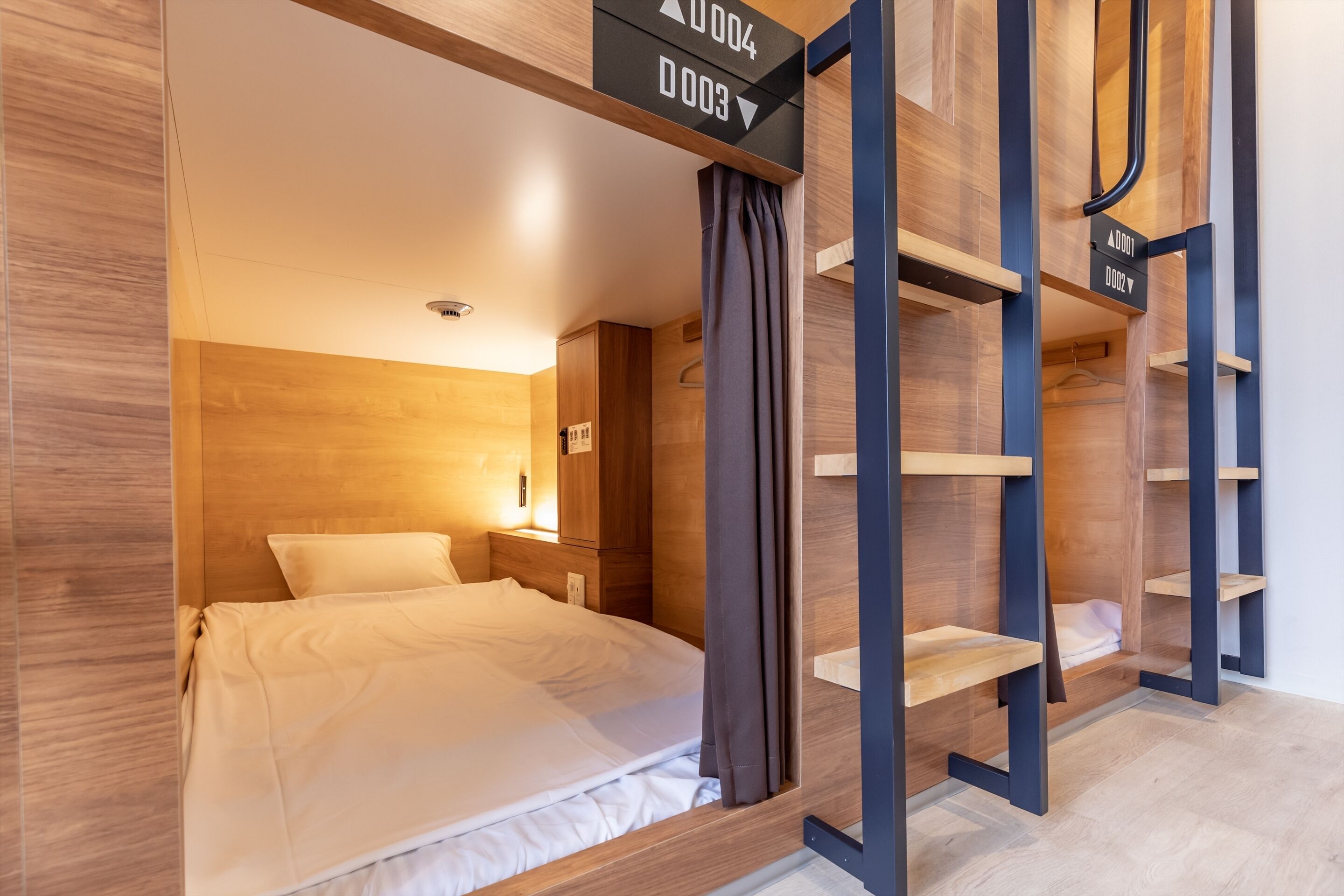 Ein modernes Hotelzimmer mit einem hölzernen Kopfteil, einem Bett mit weißen Leinen und integrierten Regalelementen.