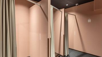 Corredor com paredes bege e carpete cinza, apresentando uma porta deslizante e uma câmera de segurança no teto.