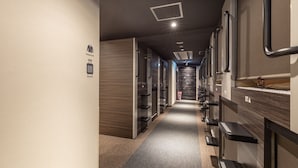 A hotel corridor with lockers, a changing room, and a staircase leading to an upper floor. - Tabist CapsuleHotel APODS Himeji Station (Himeji)