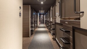 A hotel corridor with lockers, a staircase, and a modern design. - Tabist CapsuleHotel APODS Himeji Station (Himeji)