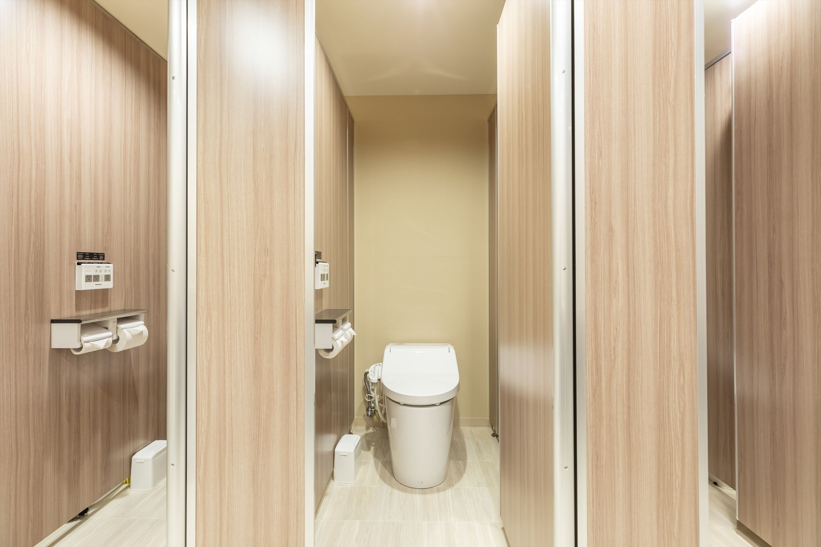 Un baño moderno con paneles de madera, un inodoro y un dispensador de toallas de papel.