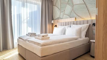 Ett modernt hotellrum med en stor säng, ett träfärgat sänggavel, ett nattduksbord och en vägg med ett geometriskt mönster.