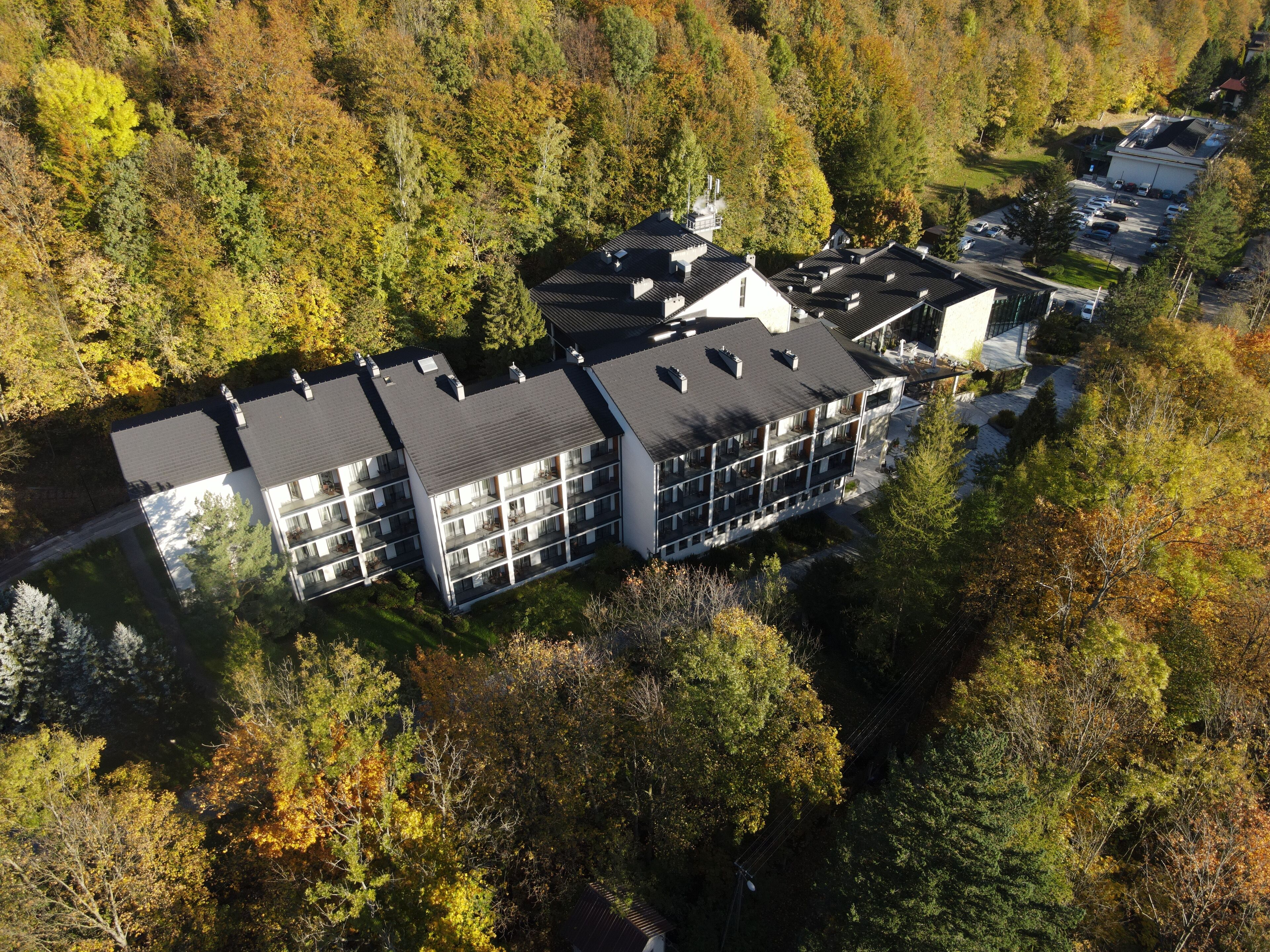 A multi-story building with a flat roof, surrounded by dense trees.