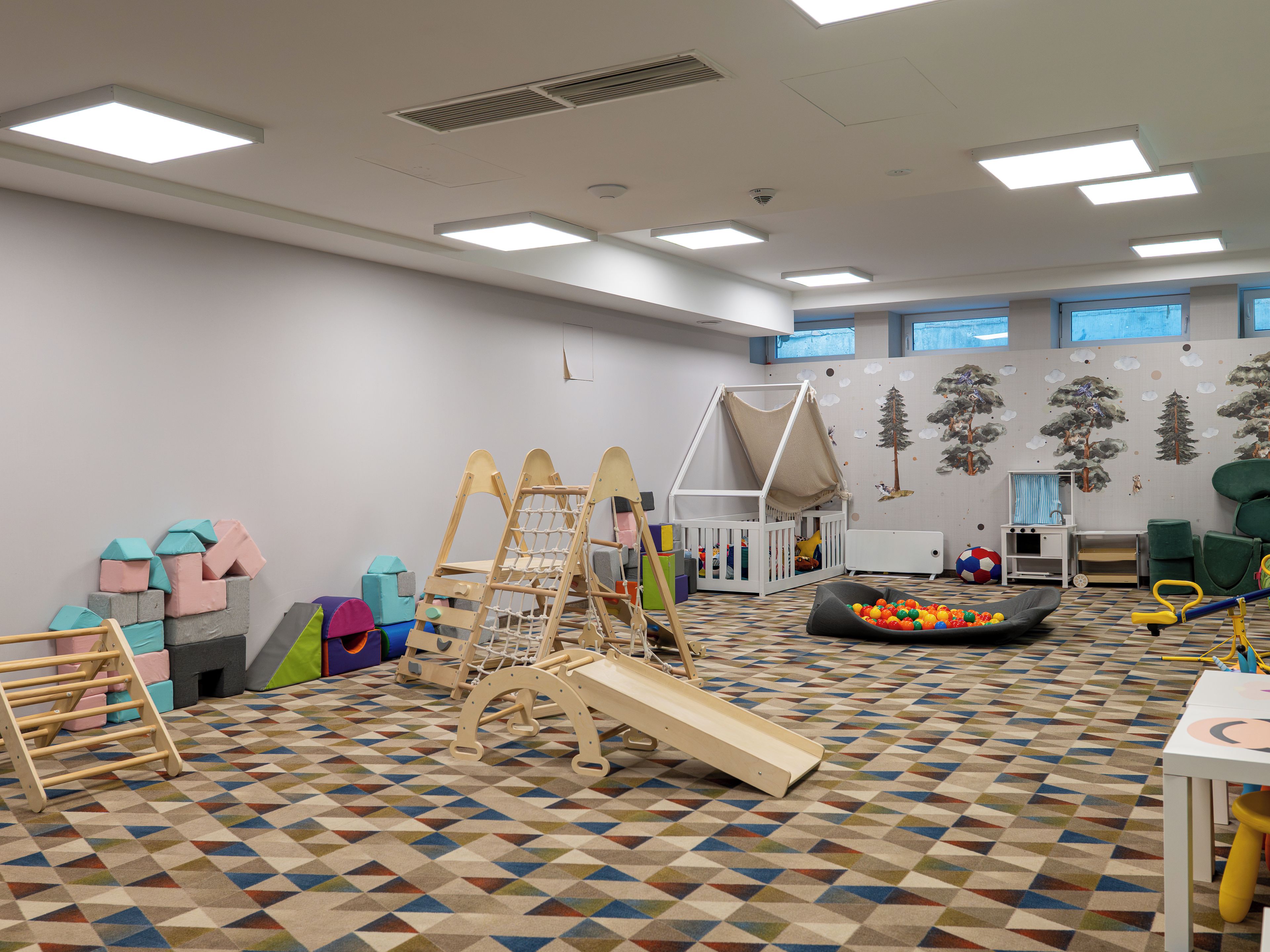 A children's playroom with a slide, climbing structures, and a ball pit.