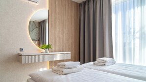 Camera d'albergo con parete in legno, uno specchio, una pianta, un comodino e un letto con asciugamani.