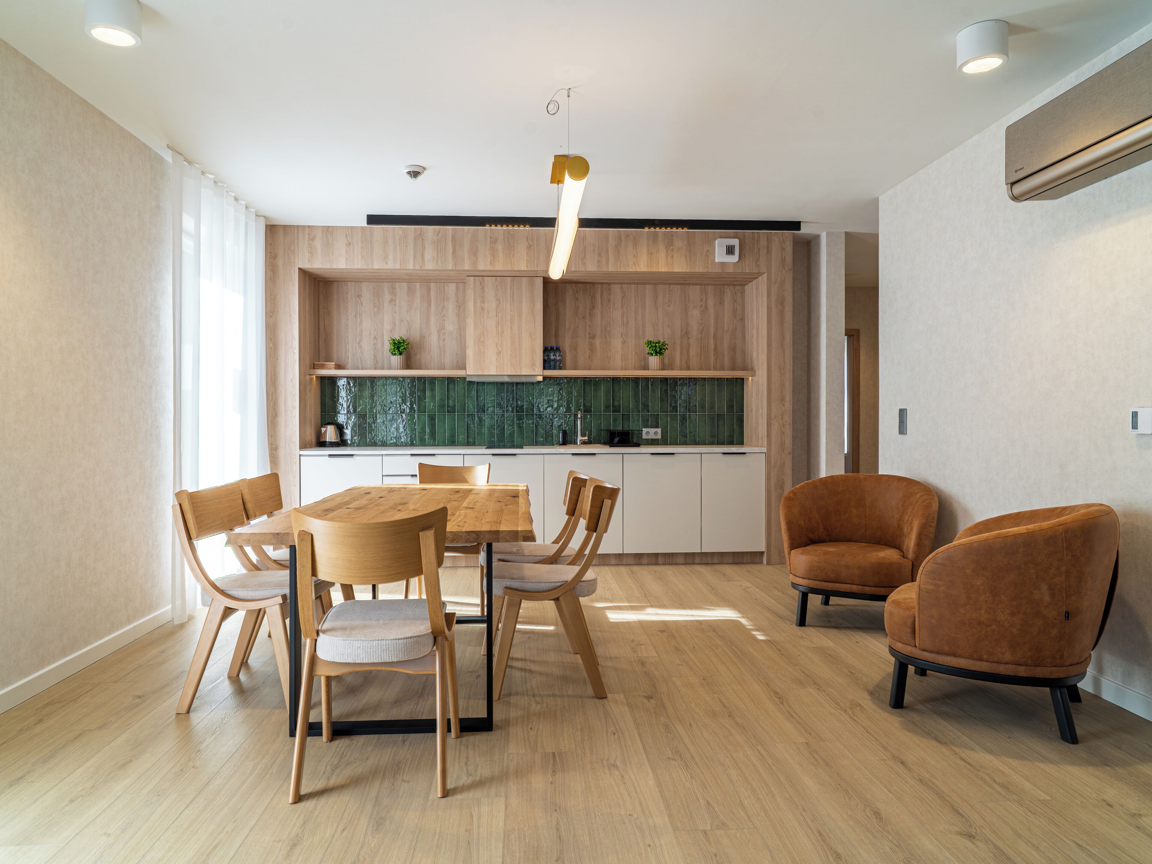 Una cocina moderna con armarios de madera, una mesa de comedor con sillas y un horno empotrado.