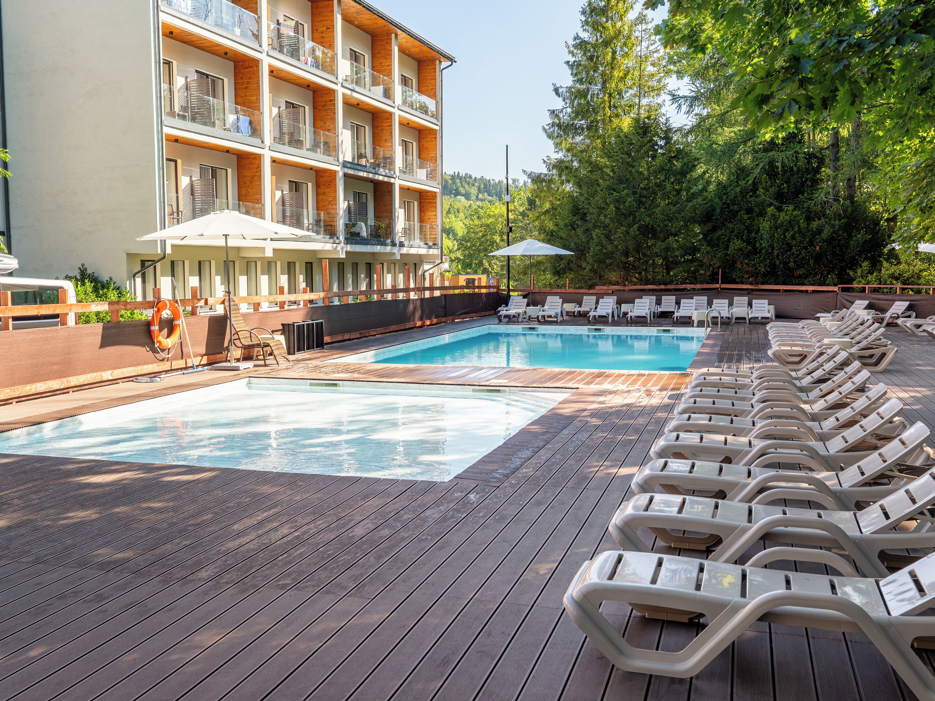 A pool area with lounge chairs and a building with balconies.