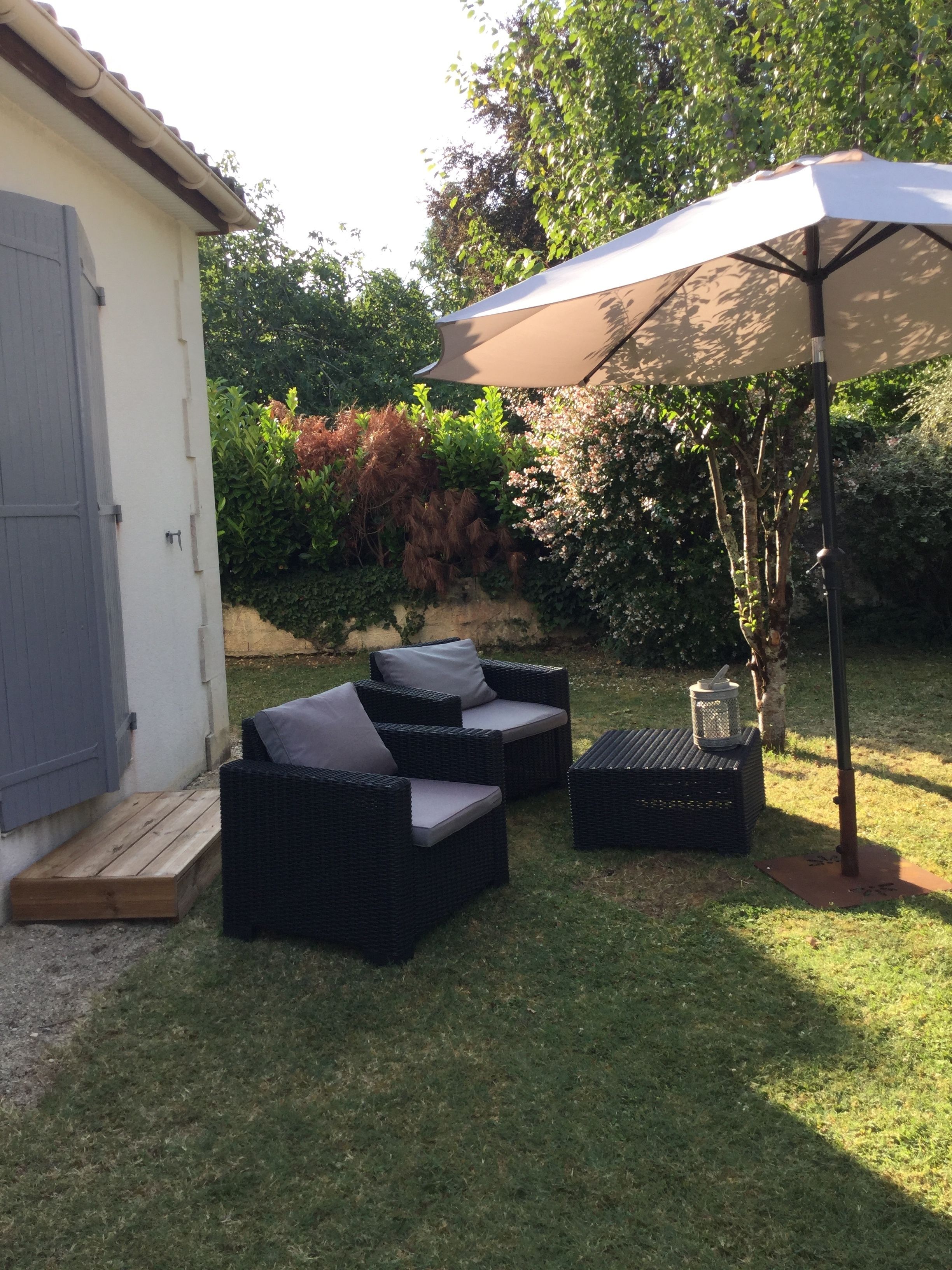 Un área de estar al aire libre con muebles de mimbre y un paraguas grande.
