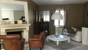 A living room with a fireplace, leather armchairs, a white sofa, and a coffee table. - La Maison des Eaux Claires (Puymoyen)