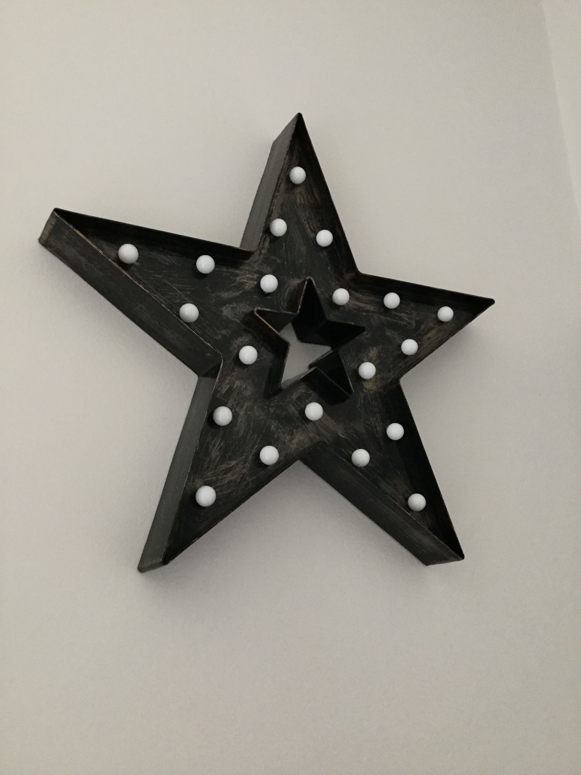 Un objeto en forma de estrella negra con puntos blancos, montado en una pared lisa.