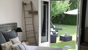A bedroom with a bed, a ladder, and a view of the garden. - La Maison des Eaux Claires (Puymoyen)