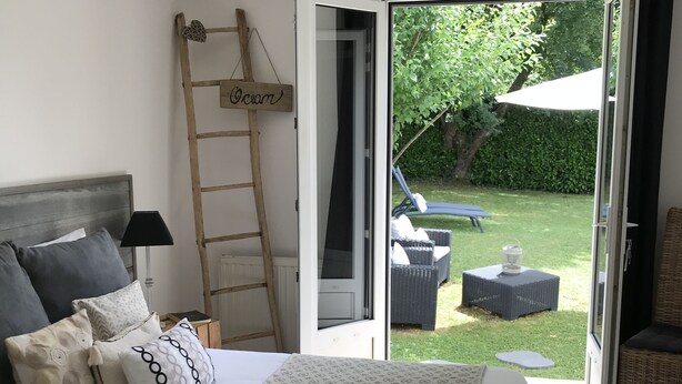 A bedroom with a bed, a ladder, and a view of the garden. - La Maison des Eaux Claires (Puymoyen)
