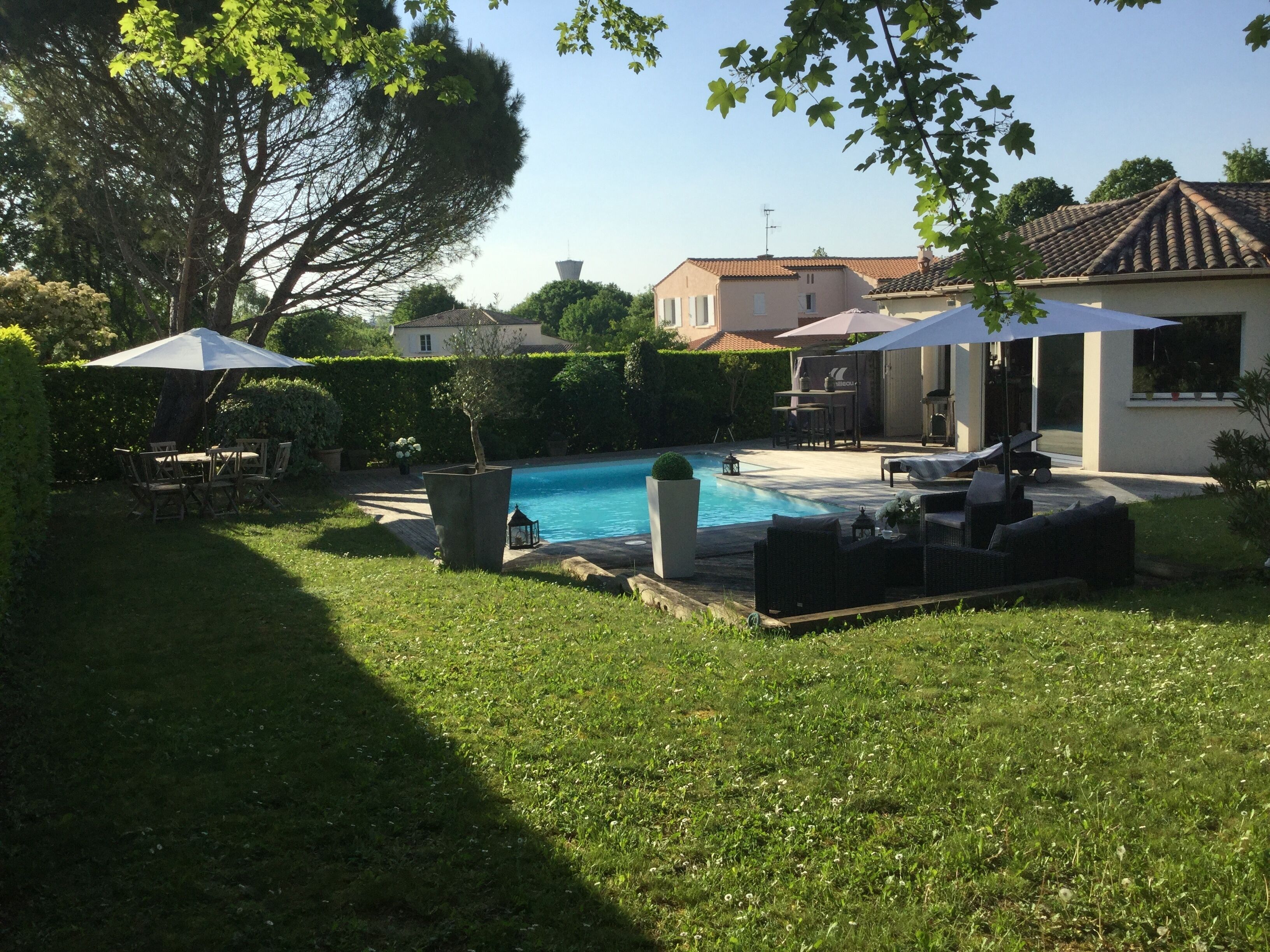Ein Garten mit Swimmingpool, Gartenmöbeln und einer Terrassenfläche.