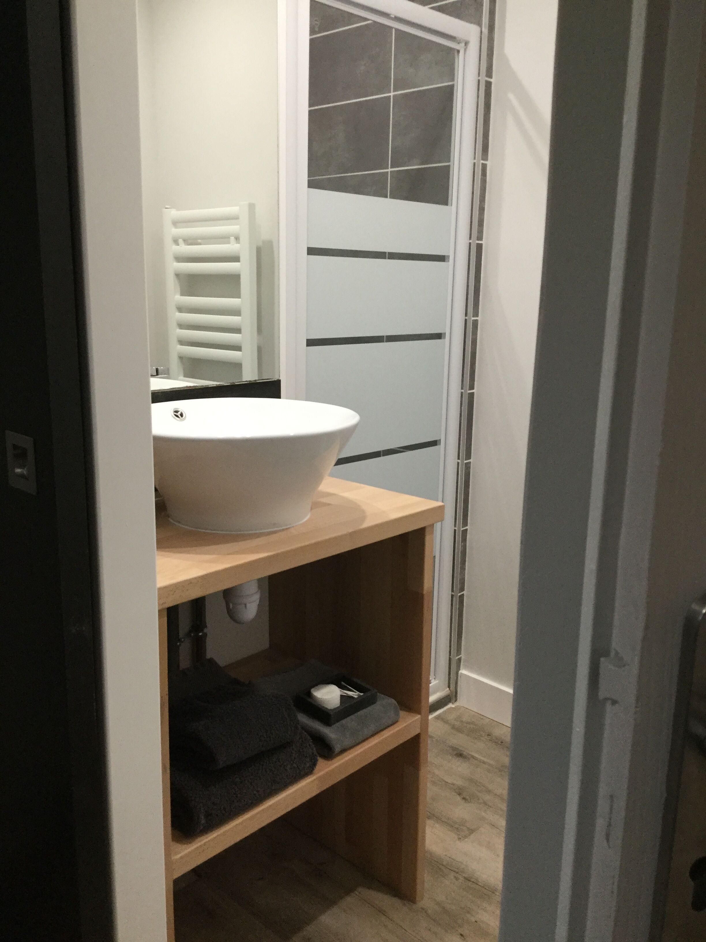 A bathroom with a white sink, a towel rack, and a shower area.