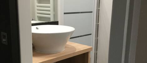 A bathroom with a white sink, a towel rack, and a shower area.